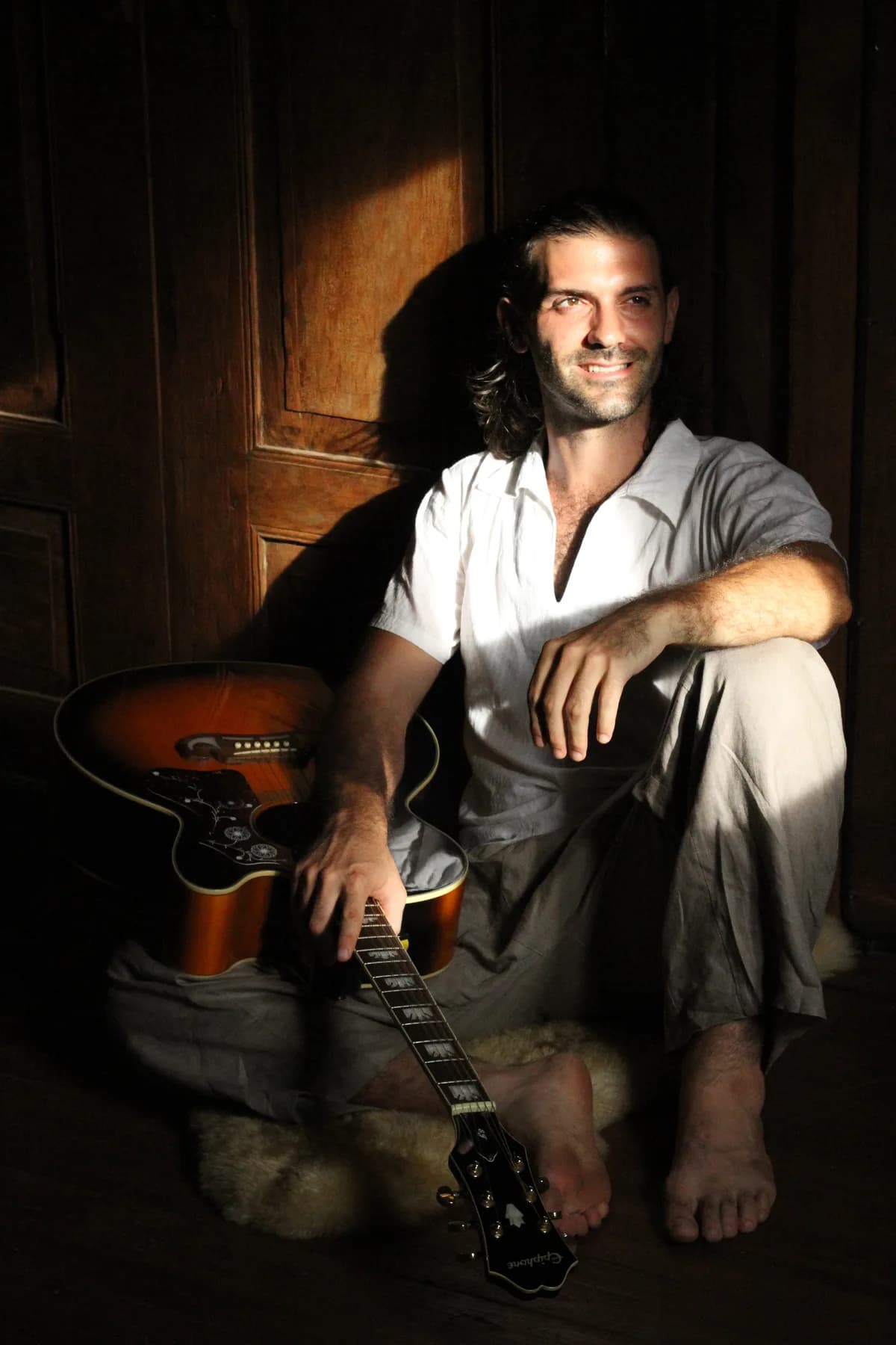 Portrait with guitar against wooden door